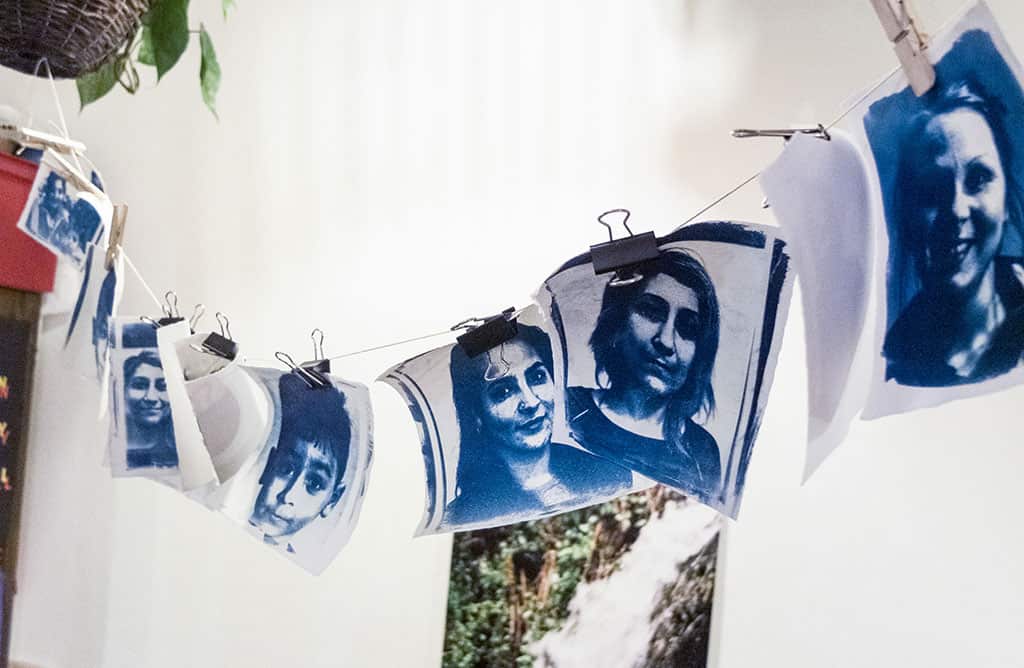 A series of blue and white mono portrait photographs, hung on a line by clips and pegs