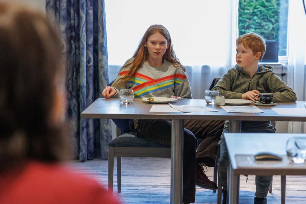 Girl asking question, boy looking on. 