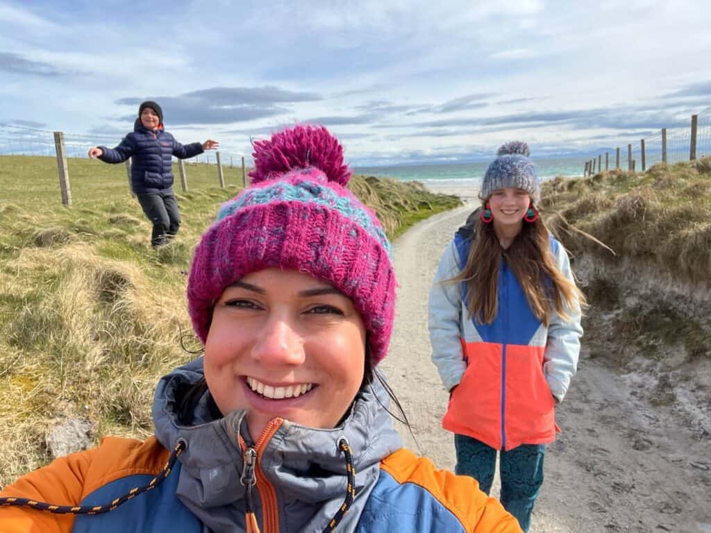 Three smiling people on a beach path with the sea in the background.
