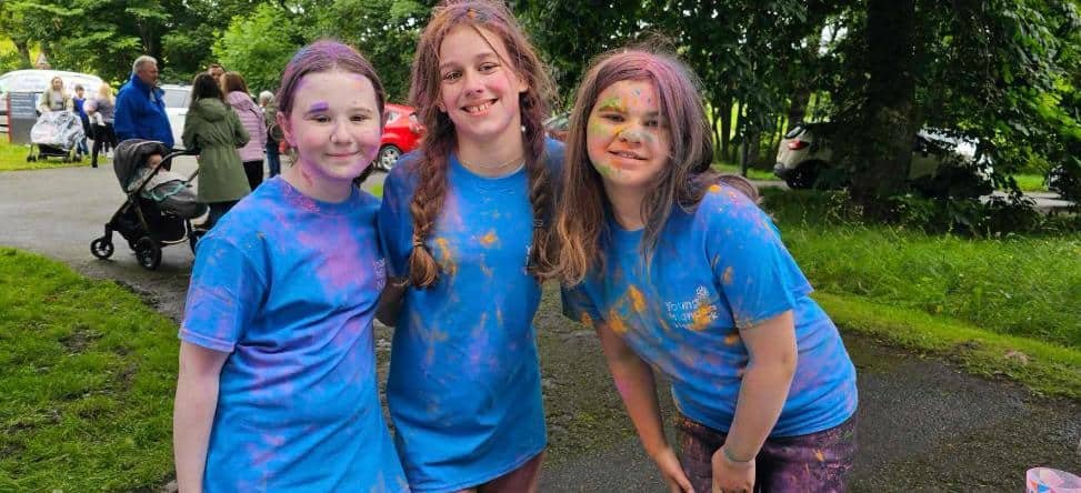 Three YIN members pose after completing the colour dash, covered in a rainbow of coloured dust.