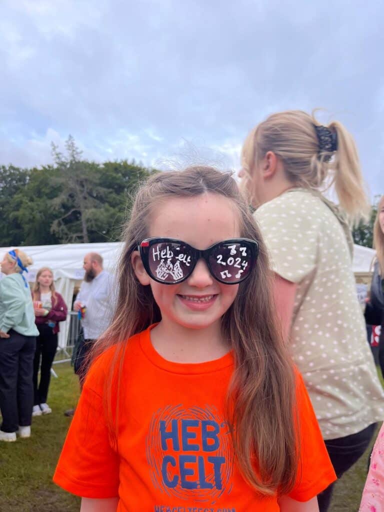 A HebCelt attendee posing with the 'HebCelt 2024' sunglasses on.