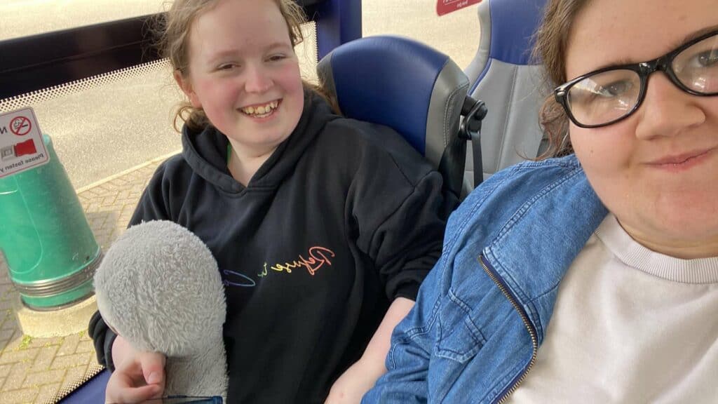 two young people on a bus smiling at camera