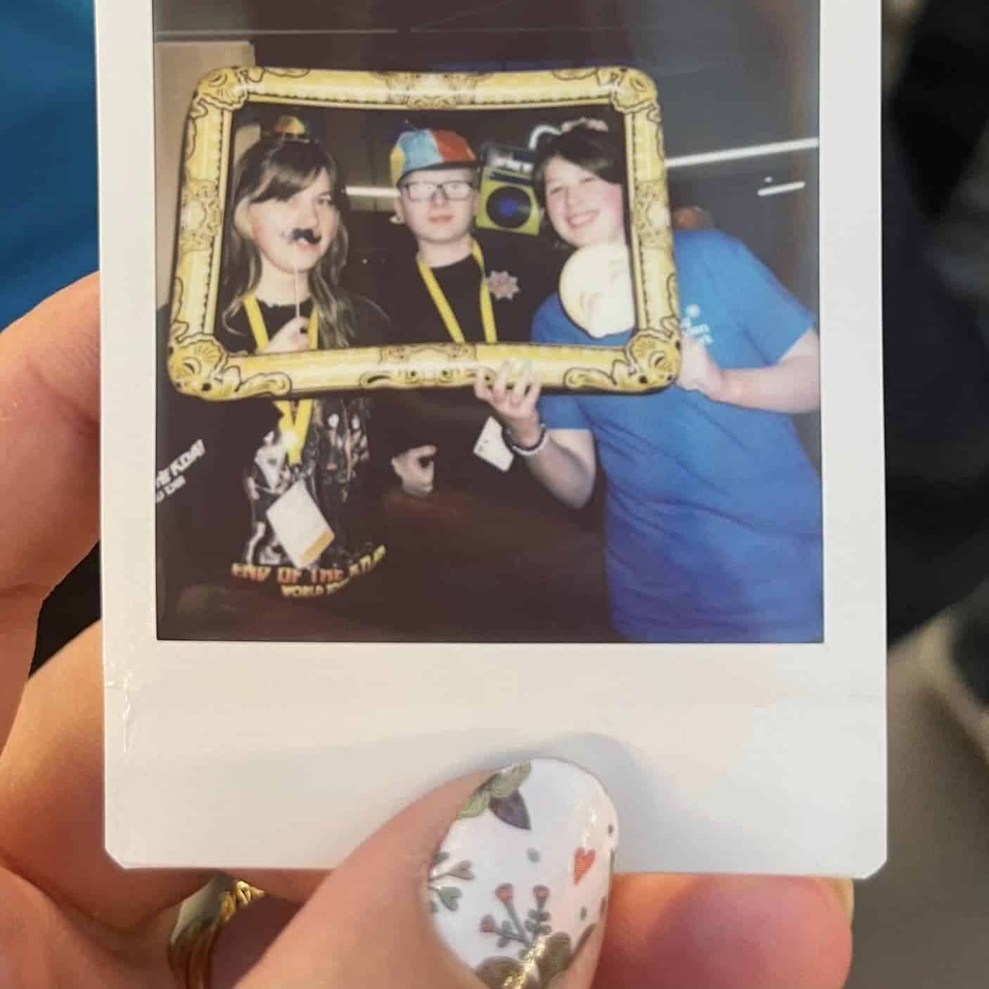 photo of a polaroid picture with a group of three young people using photo booth props