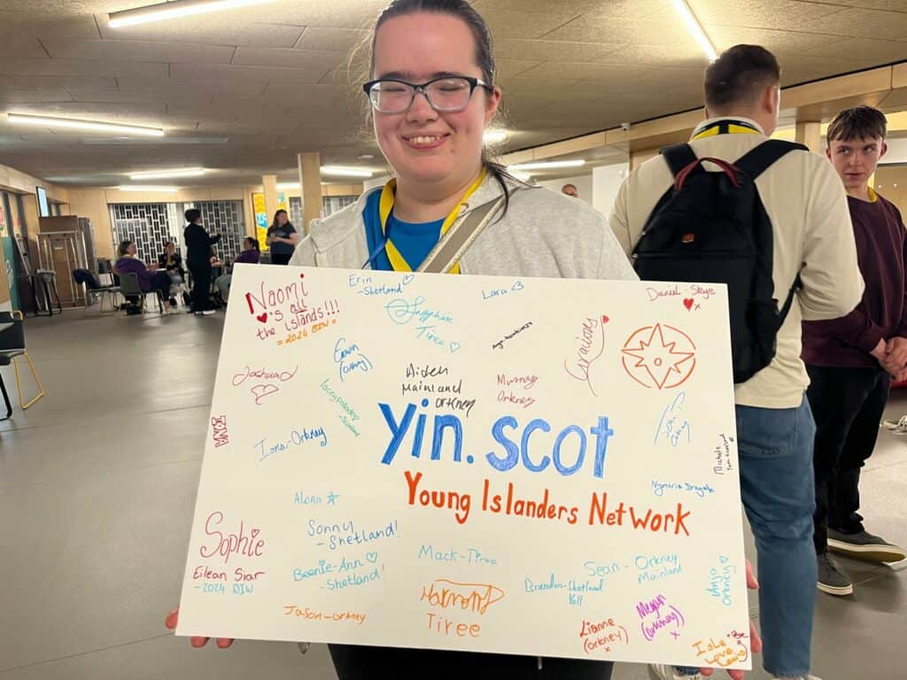 young person holding handmade YIN.SCOT banner 