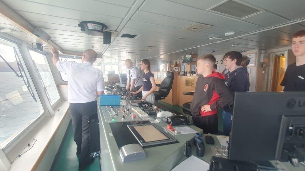 group of young people and ship's captain in the bridge