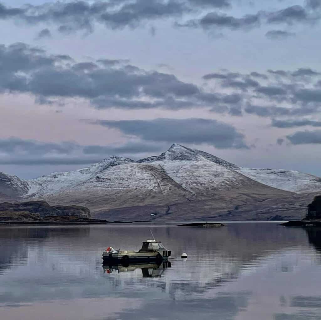 moody sunset snowy mountains and ulva ferry sitting on a still water